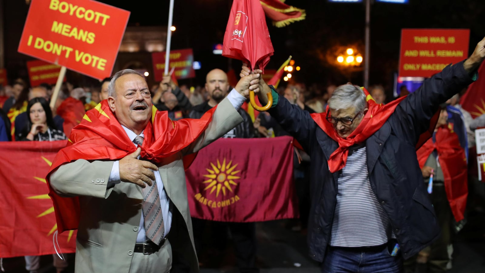 Des Macédoniens manifestent avec des pancartes et des drapeaux rouges pour inciter la population à boycotter le référendum.