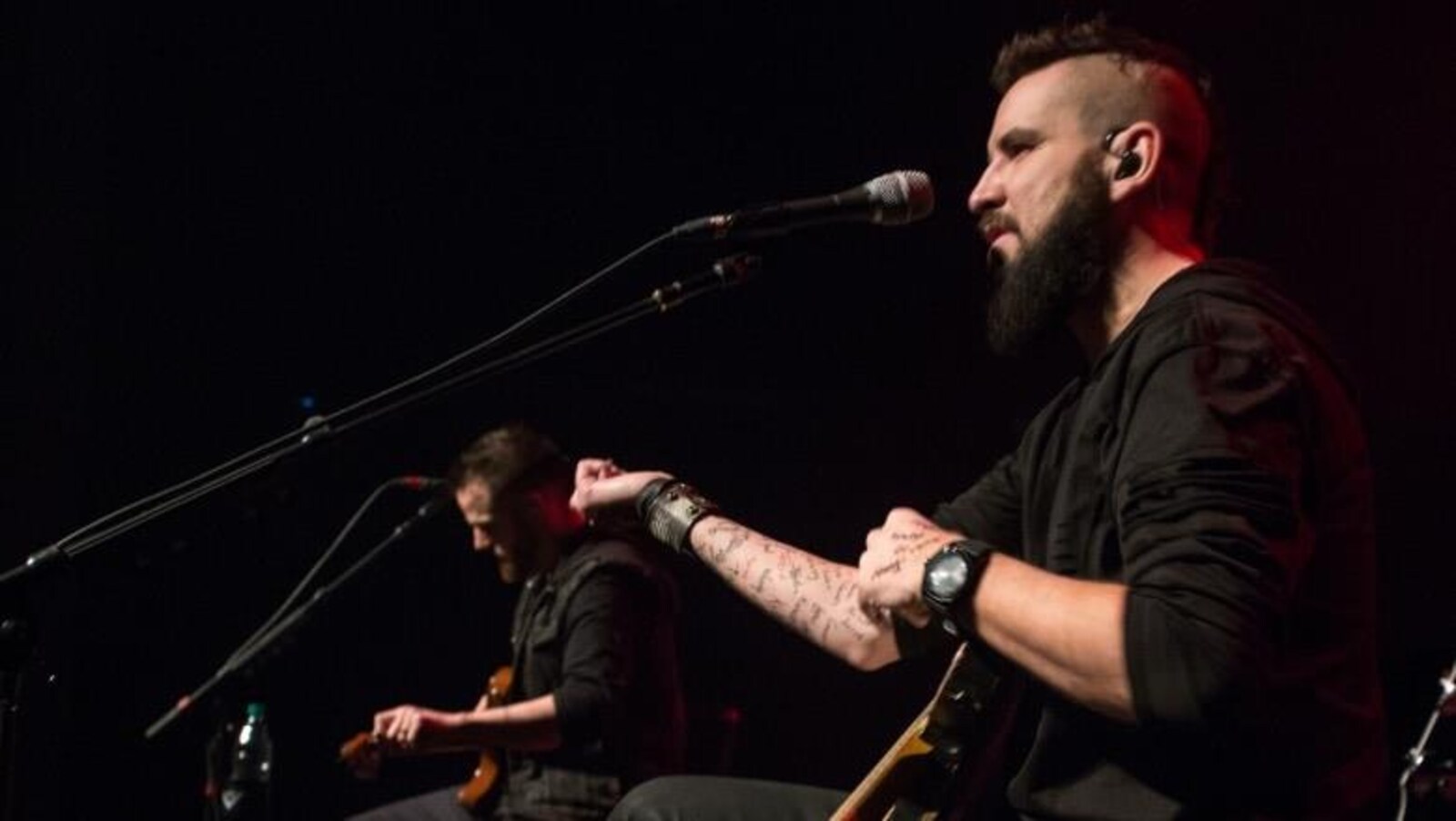 Un musicien présente son bras recouvert de prénoms tatoués.