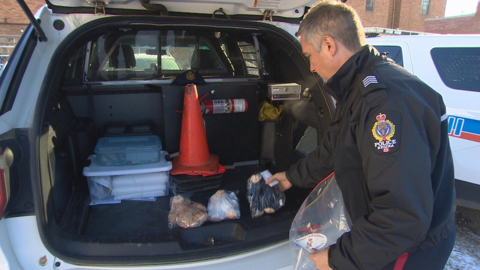 Un policier de Regina range des oursons en peluche dans sa voiture.