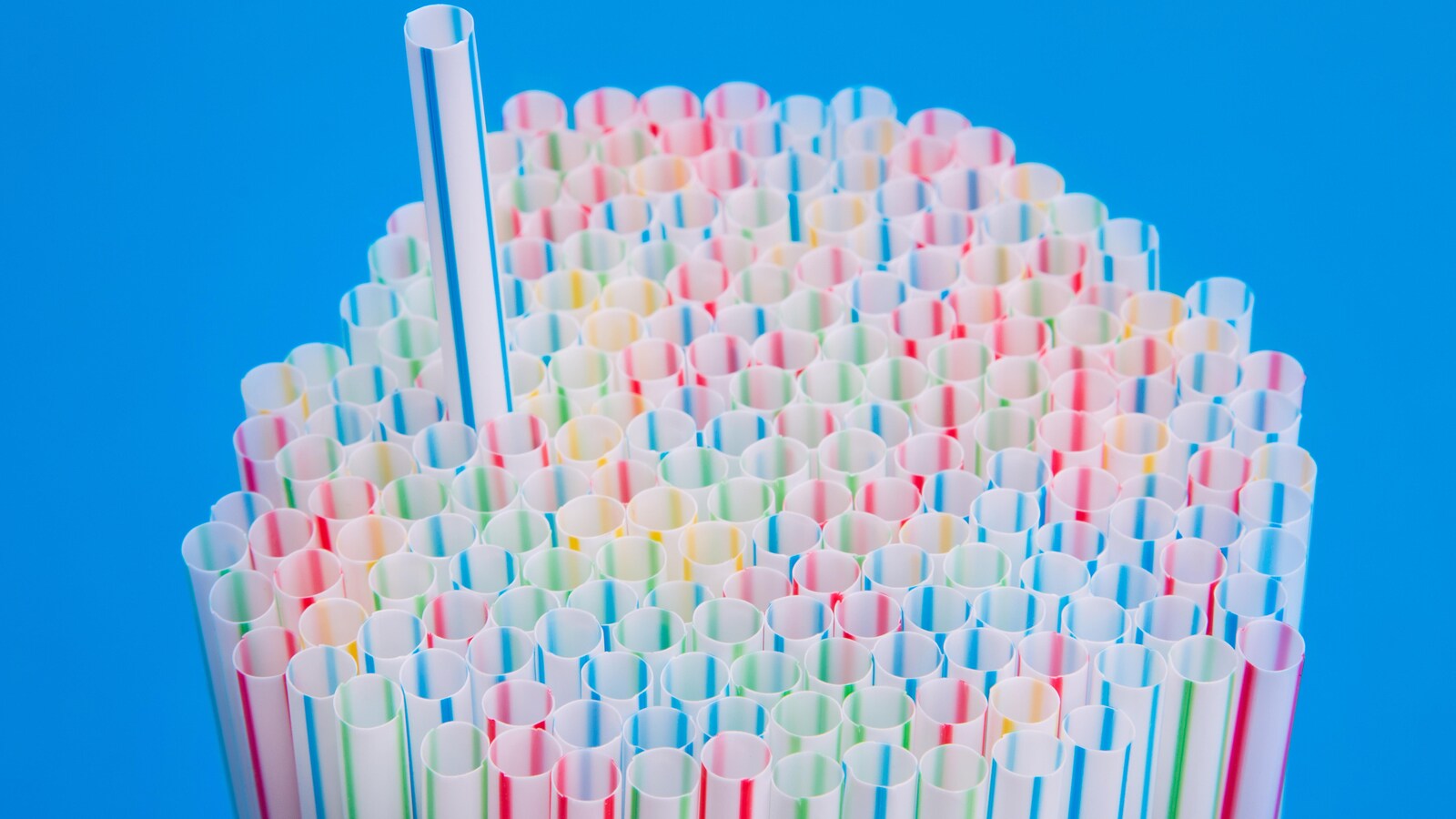 Une paille ressort d'une pile de pailles colorées.