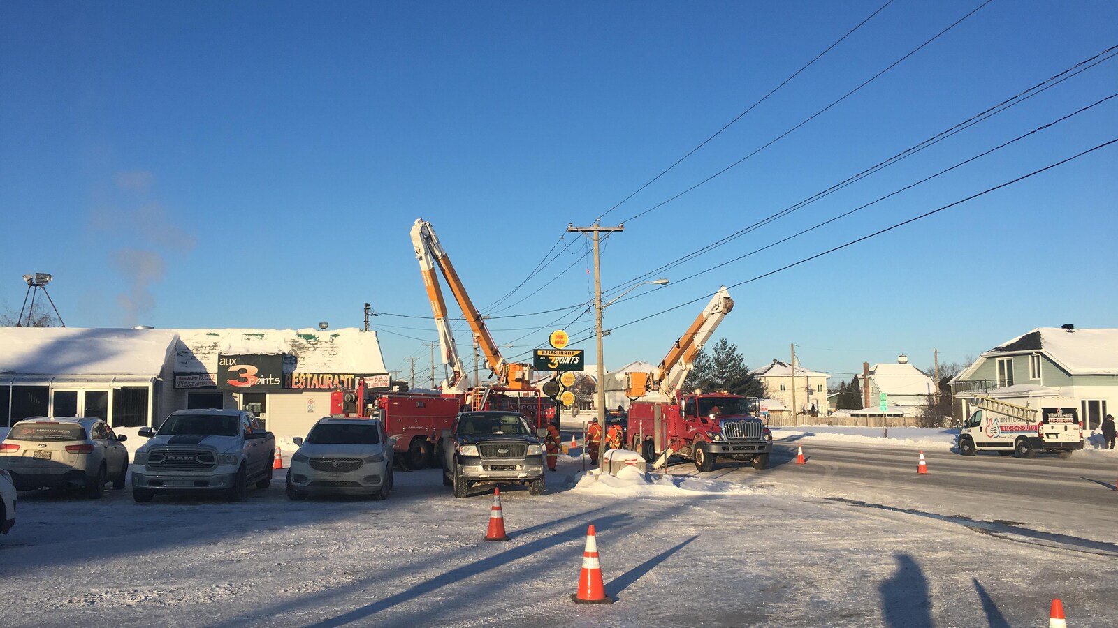 Deux camions d'Hydro Jonquière sont installés près du poteau défectueux.