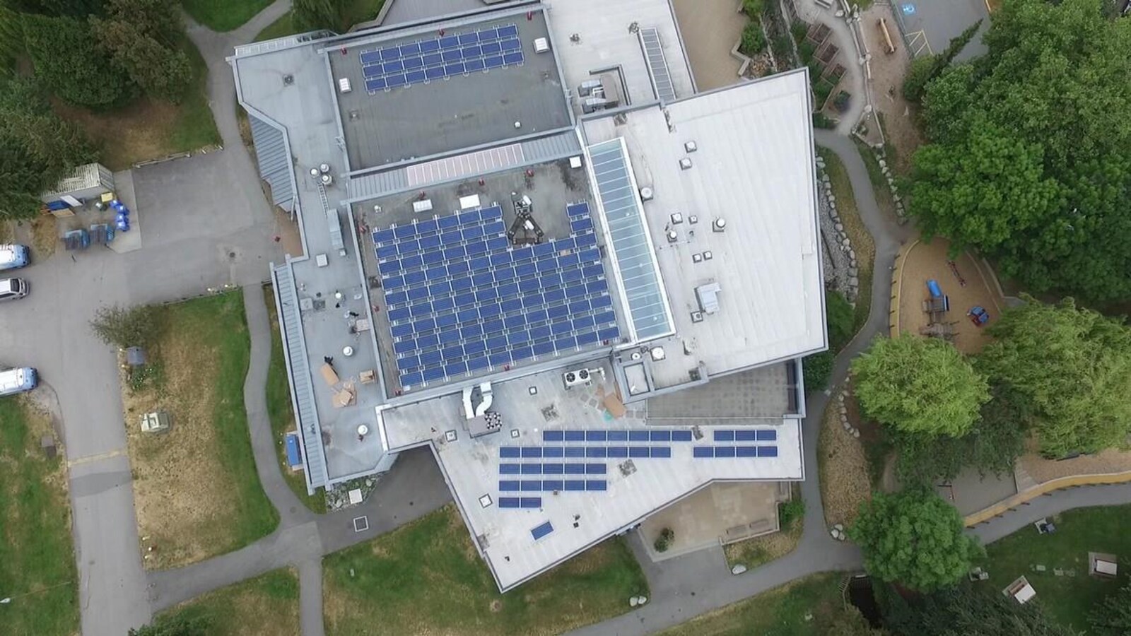 Vue aérienne du toit d'un bâtiment sur lequel sont installés plus d'une centaine de panneaux solaires.