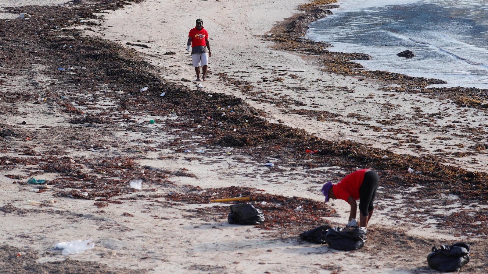 Une femme nettoie une plage à Port Moresby, capitale de la Papouasie-Nouvelle-Guinée.