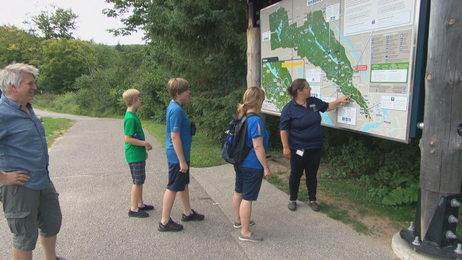 Une famille de randonneurs devant un carte du parc de la Gatineau.