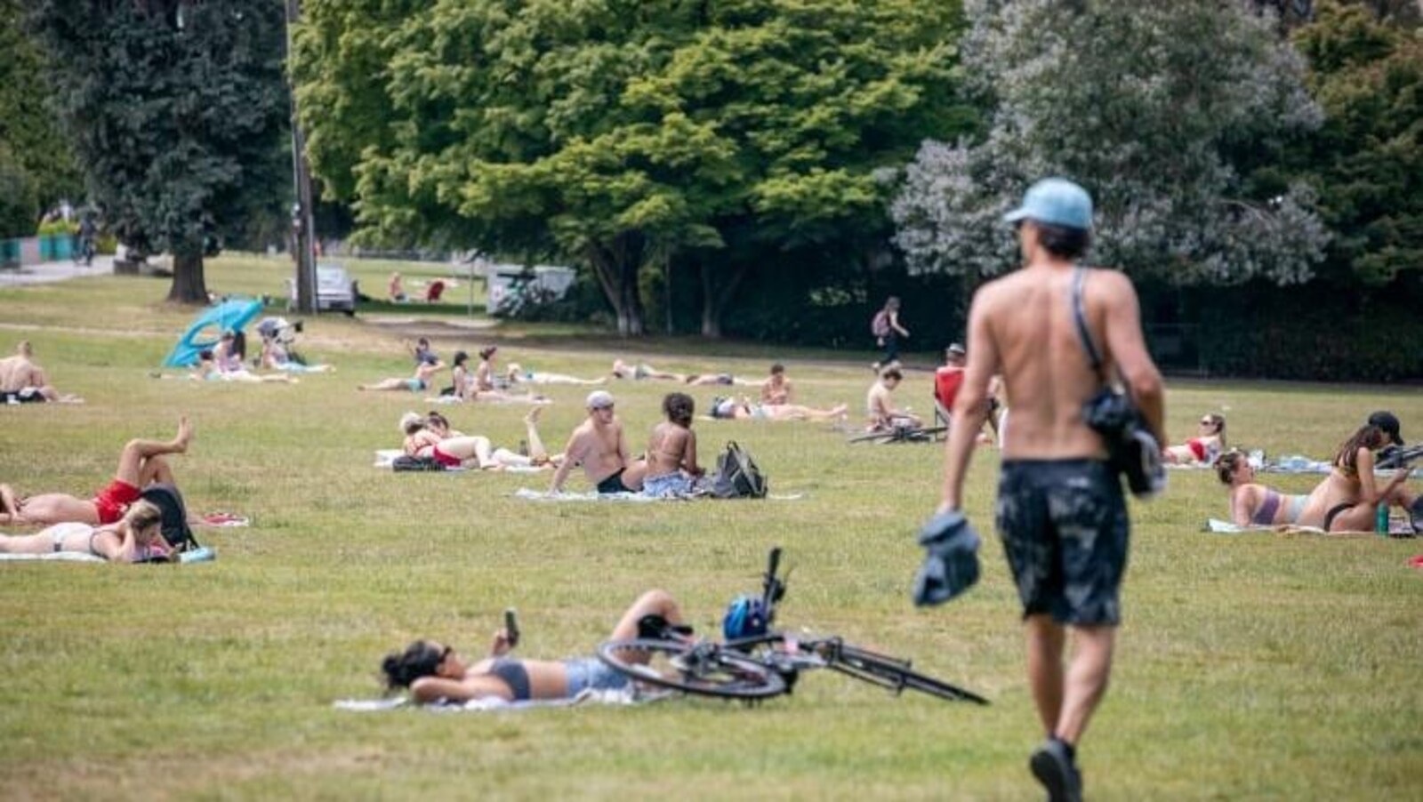 Des gens en tenues légères se prélassent dans un parc.