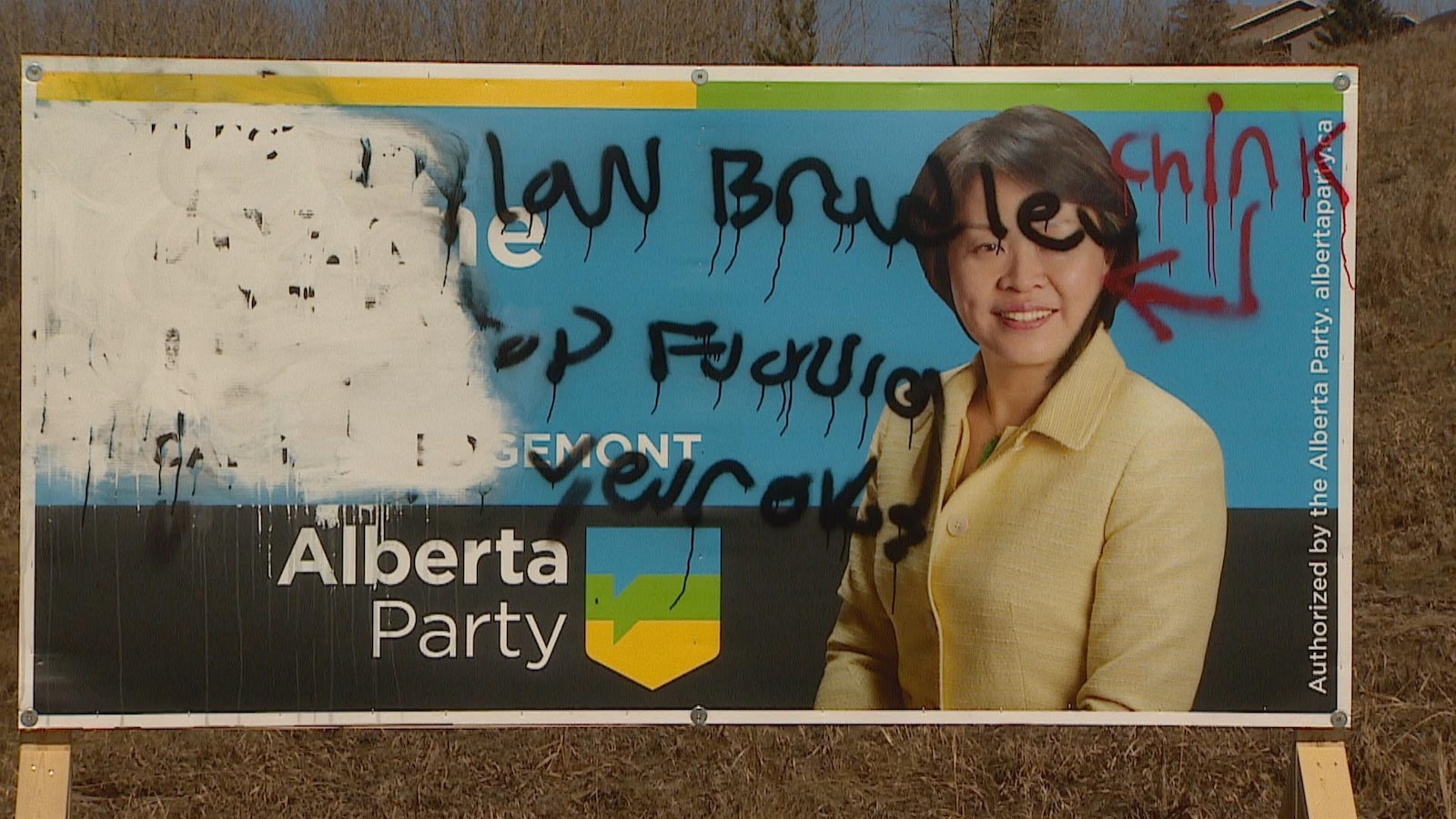 Vue sur une pancarte avec le visage d'une candidate. Elle a des traits asiatiques. Autour de son visage on voit des propos racistes ajoutés par graffiti.