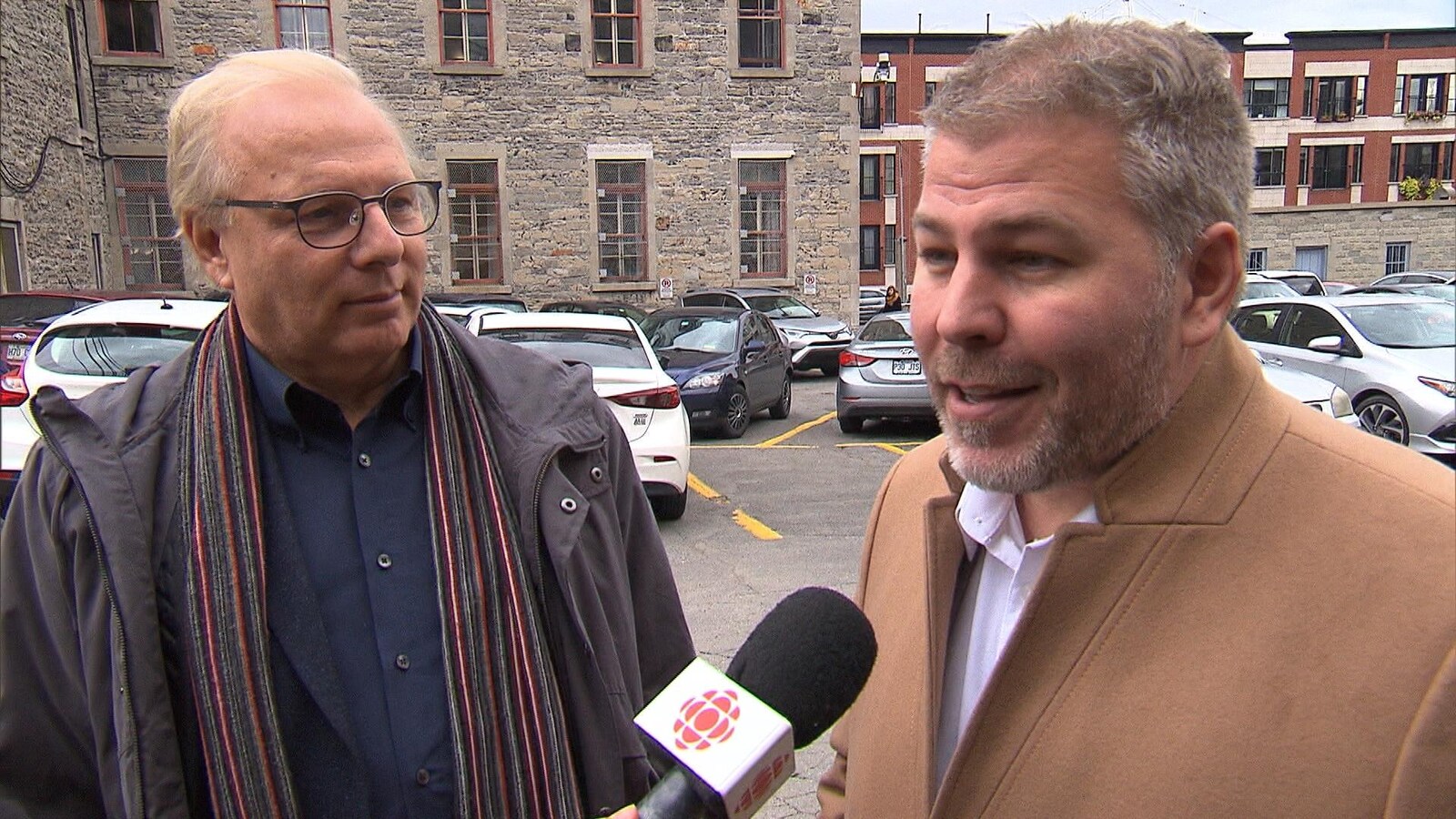 Deux hommes répondent aux questions au micro dans un stationnement du Vieux-Montréal