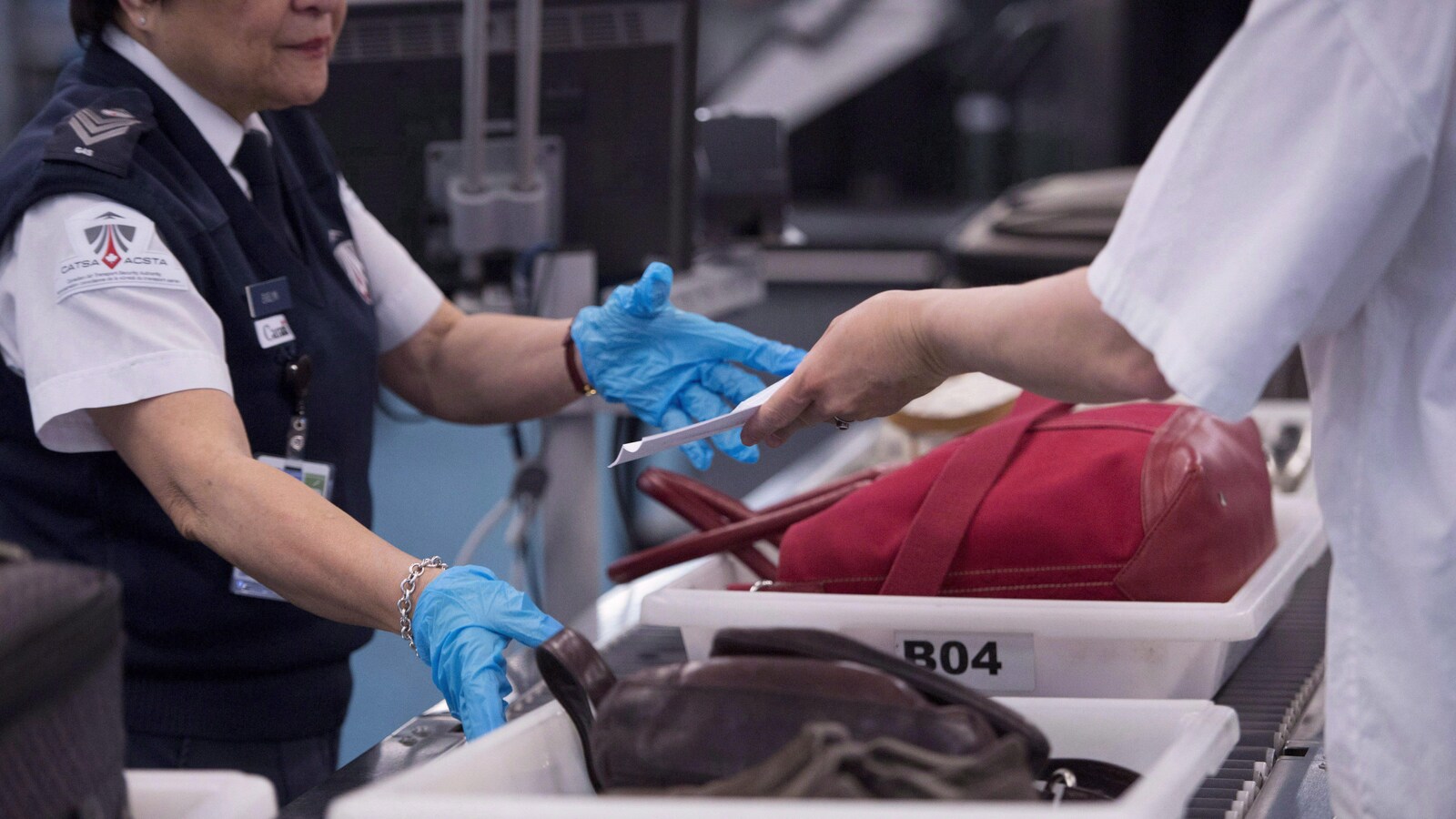 Photo d'un passager qui montre sa carte d'embarquement à une employée de la sécurité.