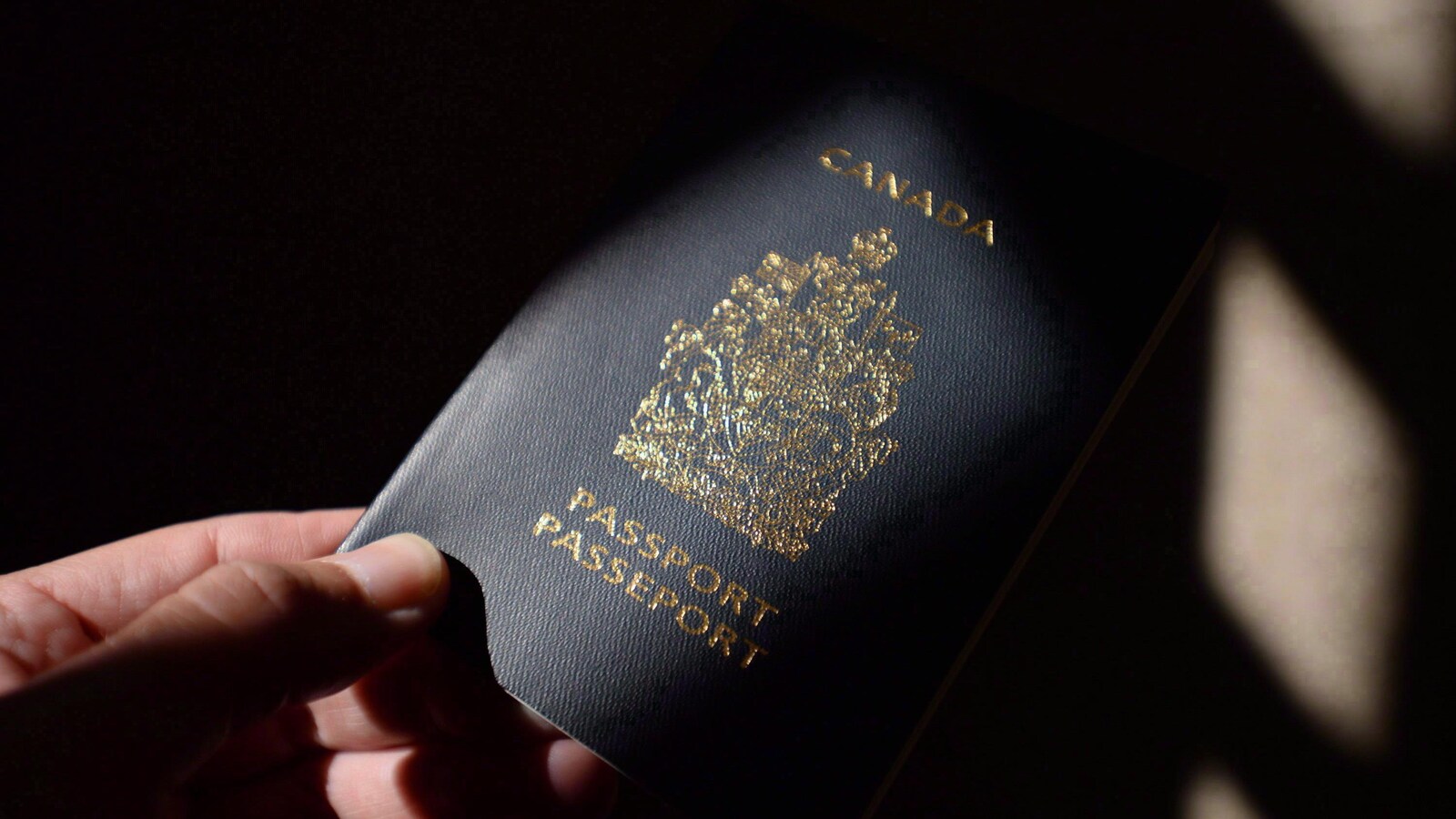 Une main qui tend un passeport canadien