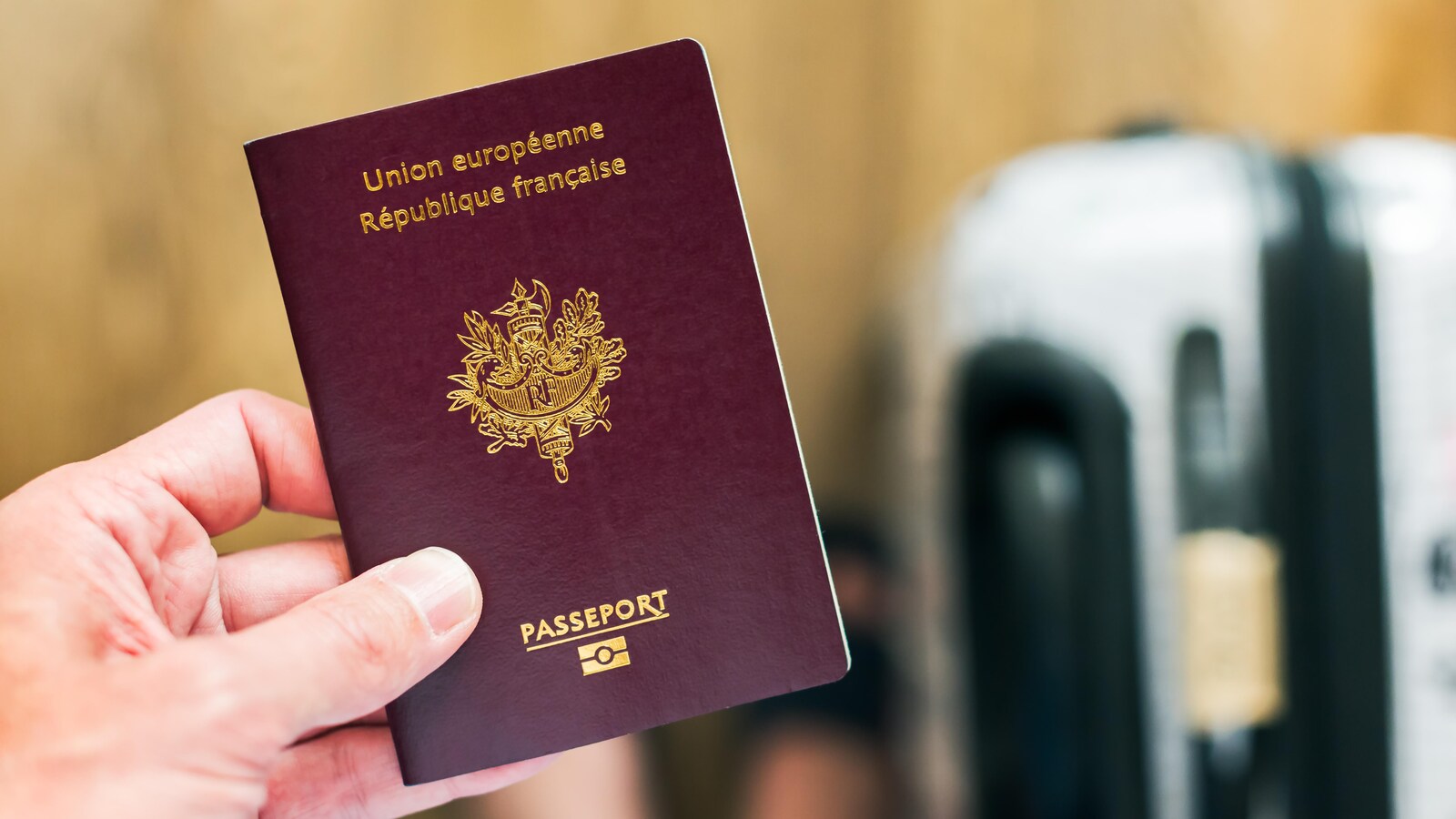 Un homme tenant un passeport français.