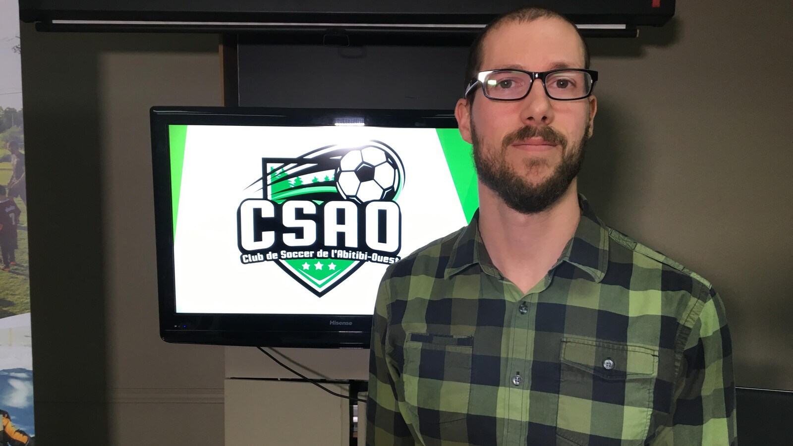 Un homme pose devant le logo de la CSAO.