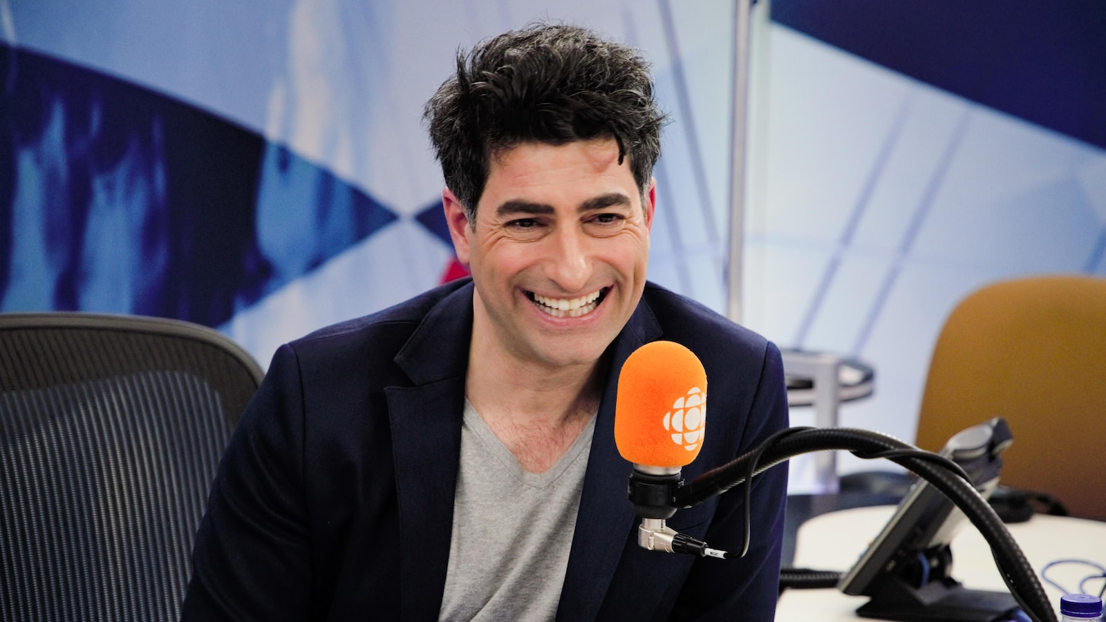 L'animateur Patrick Masbourian, devant un micro d'ICI Première dans un studio de la Maison de Radio-Canada.