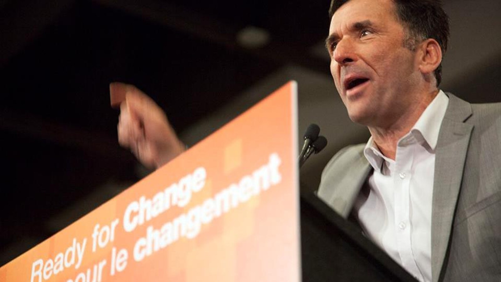 Un homme s'exprimant sur un podium orange