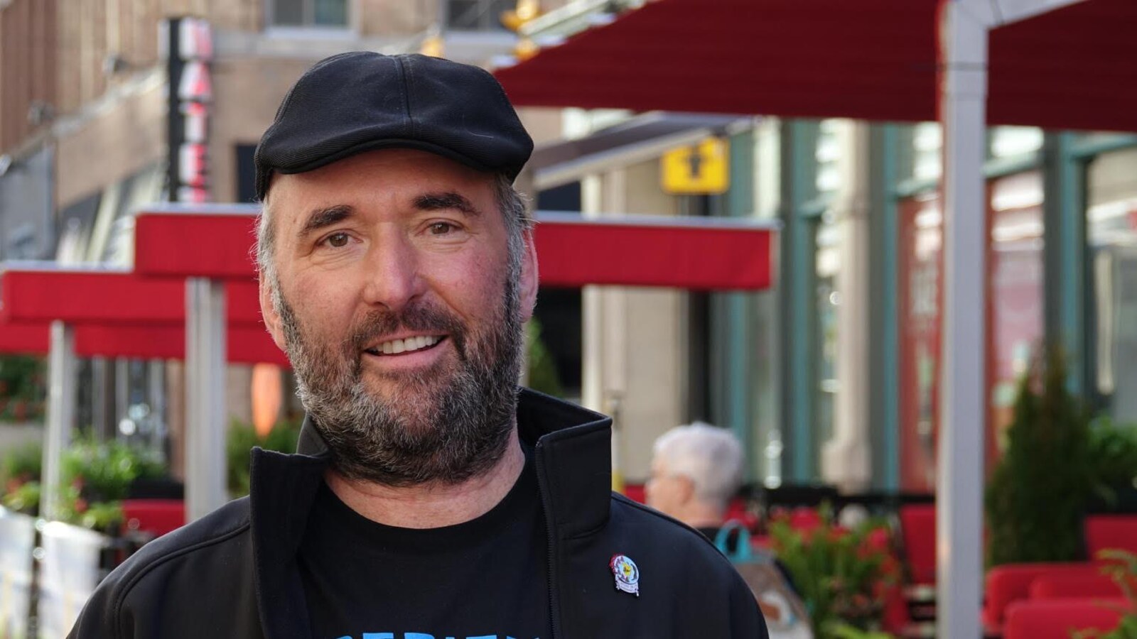 Un homme avec une casquette pose pour une photo.