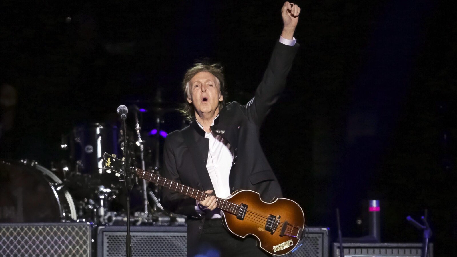 Paul McCartney tient sa guitare d'une main et lève le poing de l'autre, lors d'un concert en 2017.