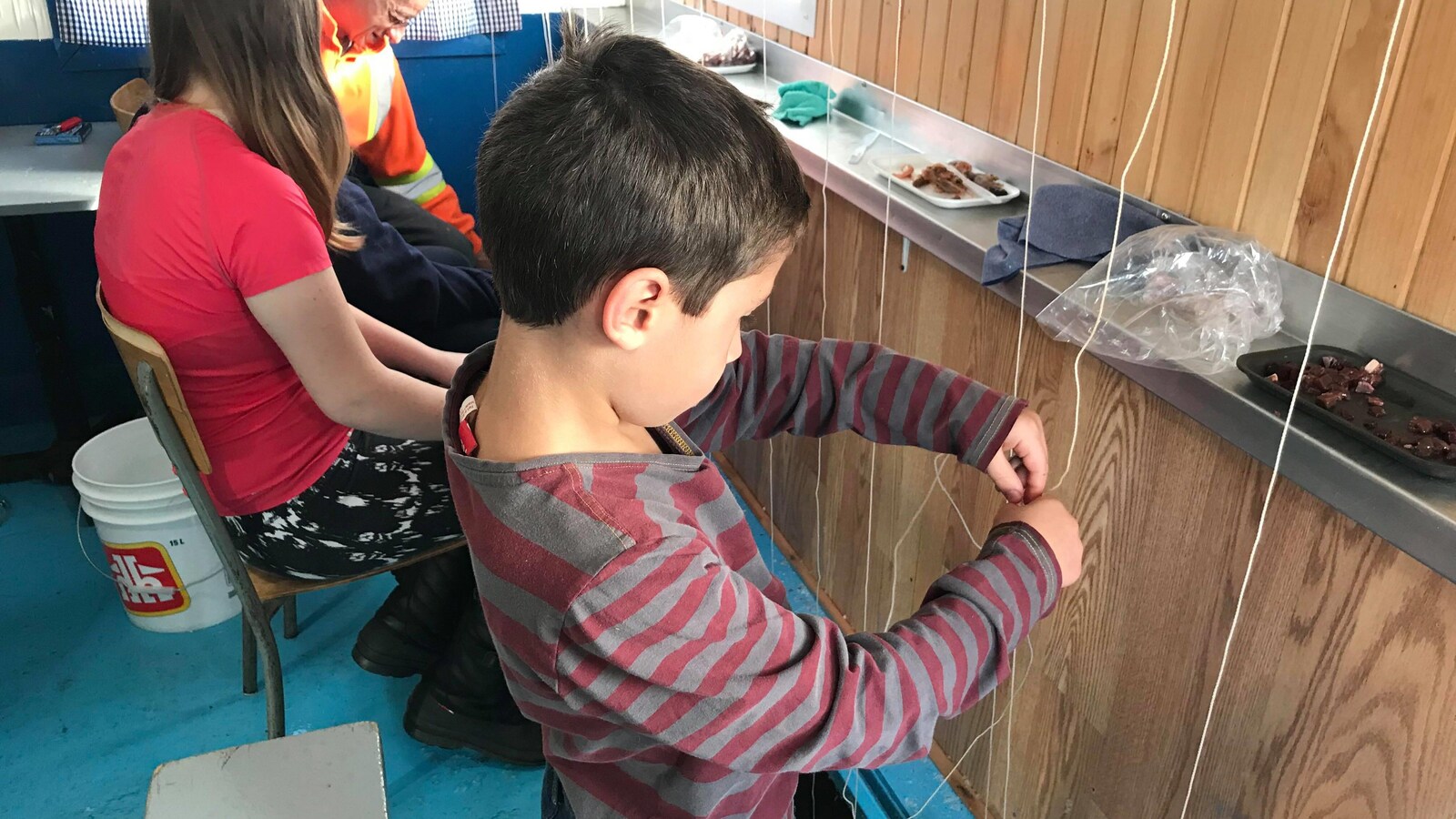 Enfant qui pêche dans une cabane avec sa famille.