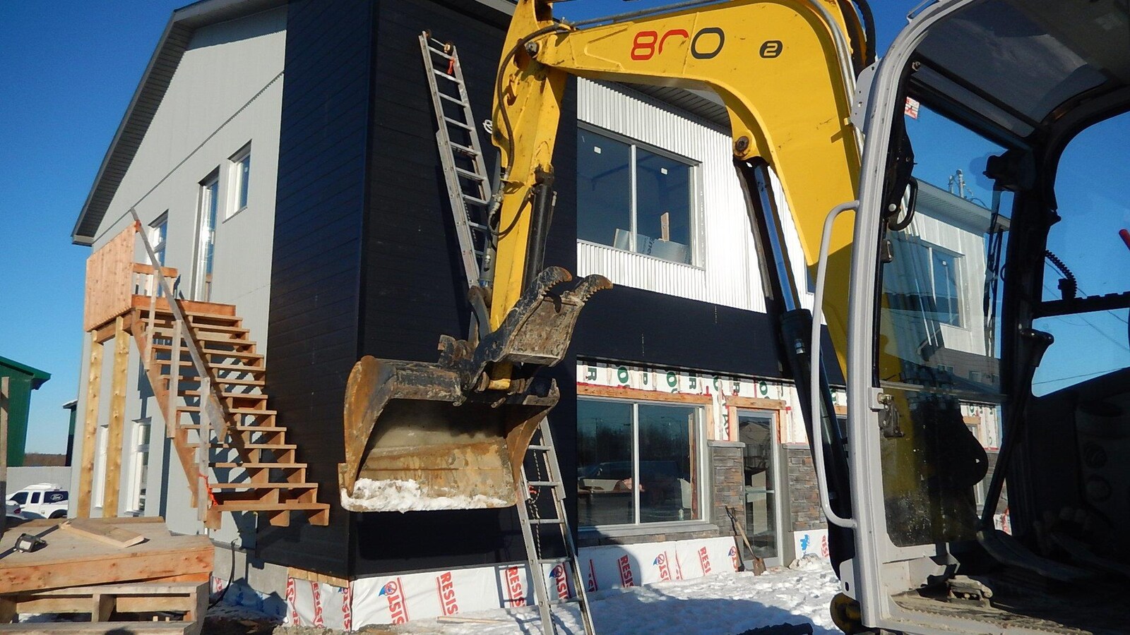 Une pelle mécanique devant un bâtiment en construction.