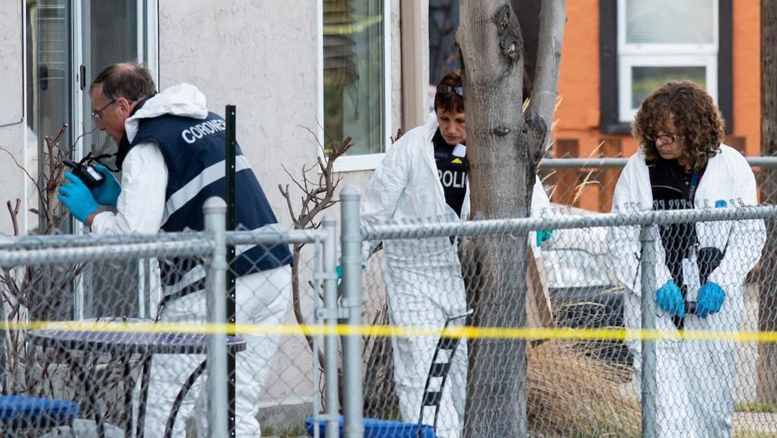 Trois agents travaillent dans une cour à ramasser des preuves.