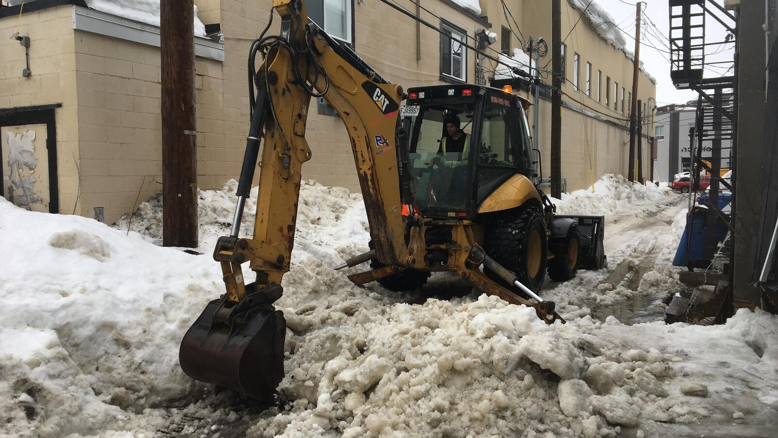 Une pelle mécanique dégage de la glace dans une ruelle.