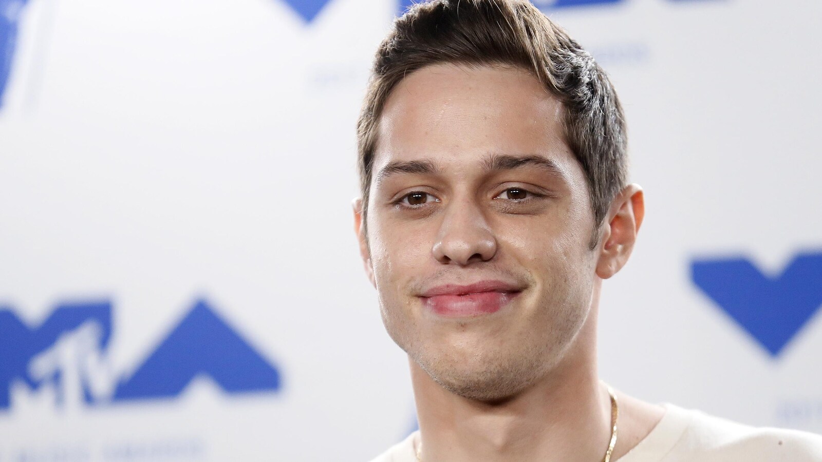 Le comédien Pete Davidson prenant la pose devant les caméras lors d'un événement médiatique.
