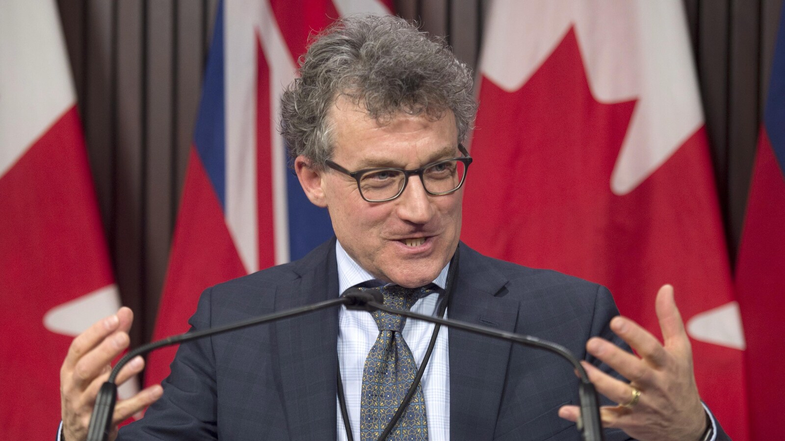 Photo d'un homme portant des lunettes devant des microphones