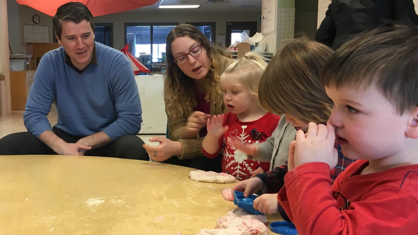 Un homme et une femme sont assis à une table de jeu avec des enfants qui s'amusent avec de la pâte à modeler.