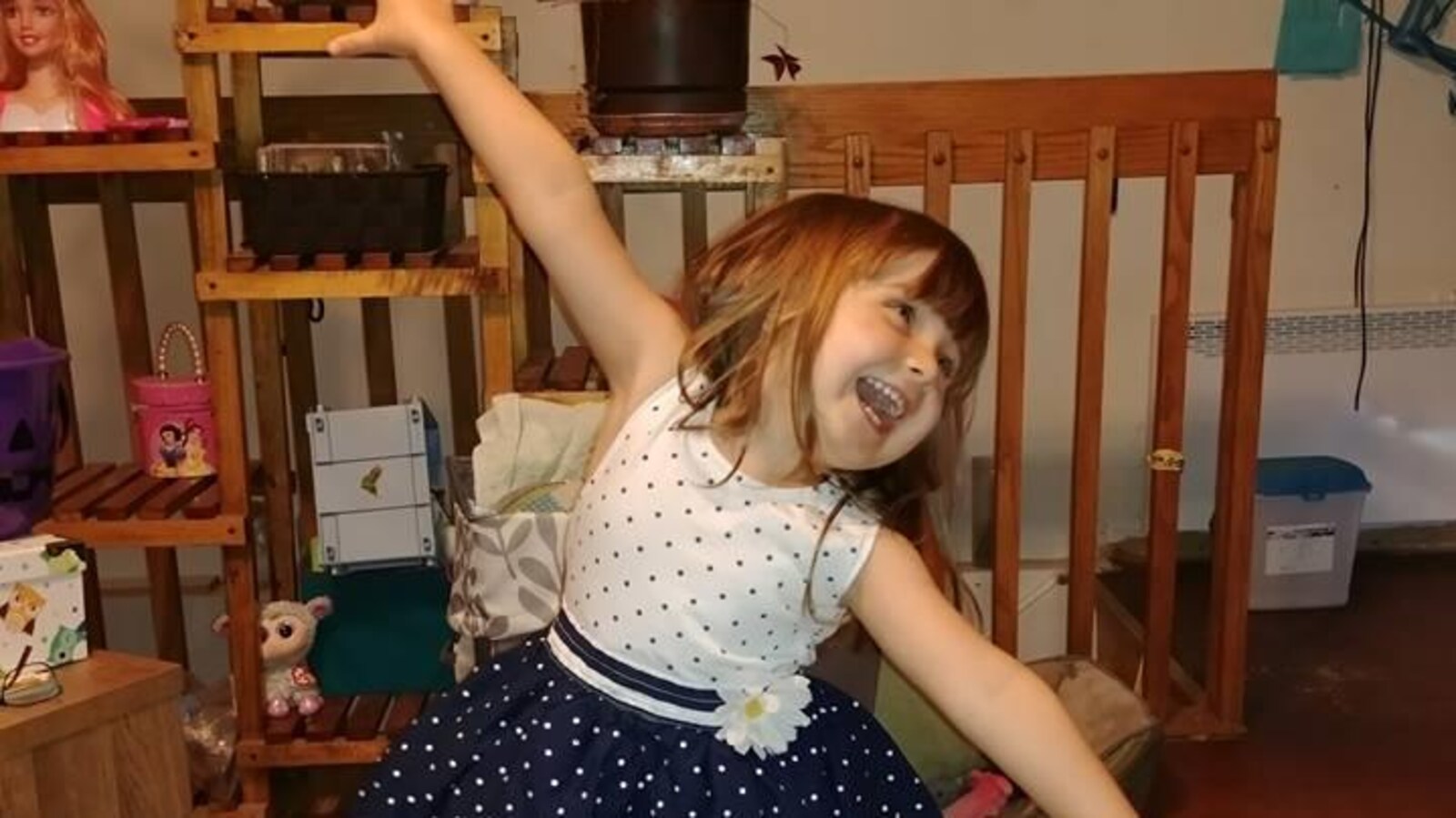 Une petite fille en robe sourit pour la caméra.