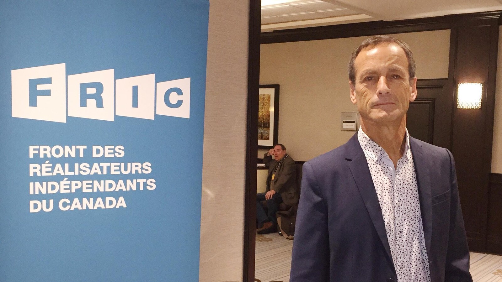 Phil Comeau à côté d'une affiche du FRIC.