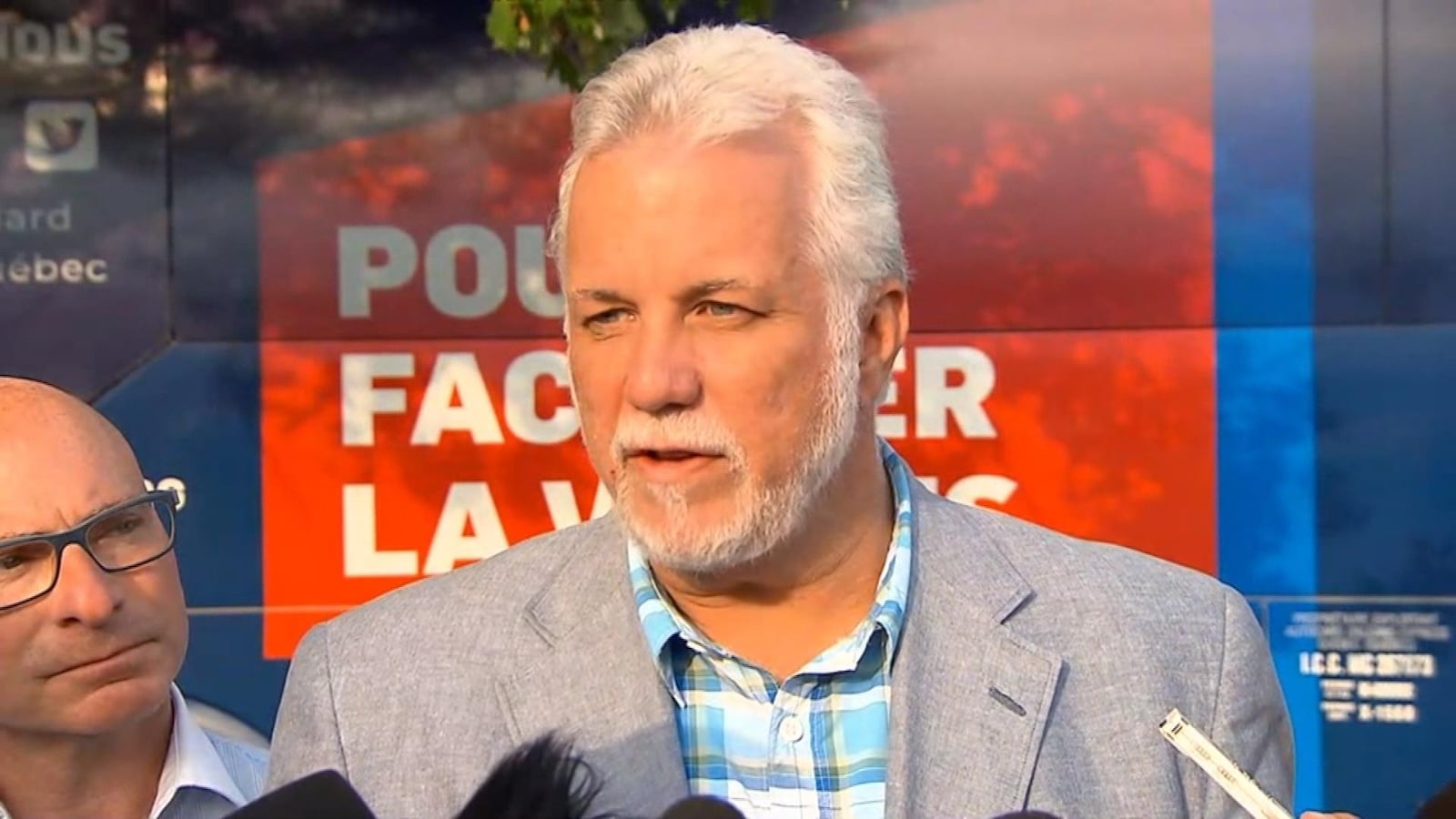 Philippe Couillard parle aux médias devant son autobus de campagne.