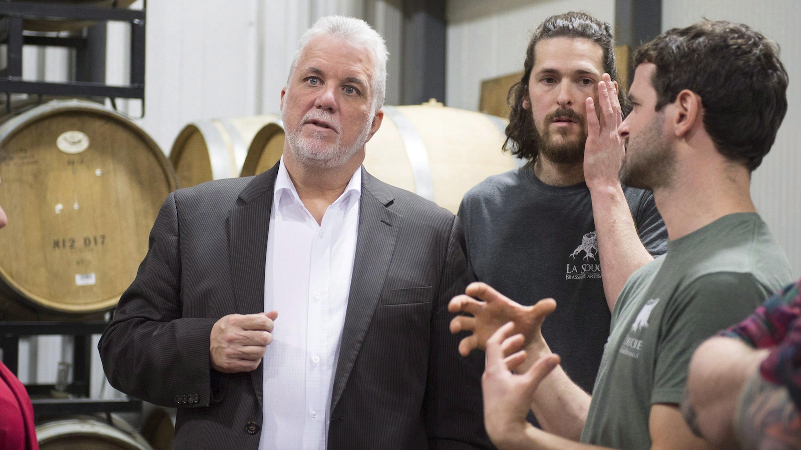 Quebec Premier Philippe Couillard chats with owners Antoine Bernatchez, centre, and Olivier Giguere during a visit of a micro-brewery in Stoneham, Quebec on Thursday, March 1, 2018. THE CANADIAN PRESS/Jacques Boissinot