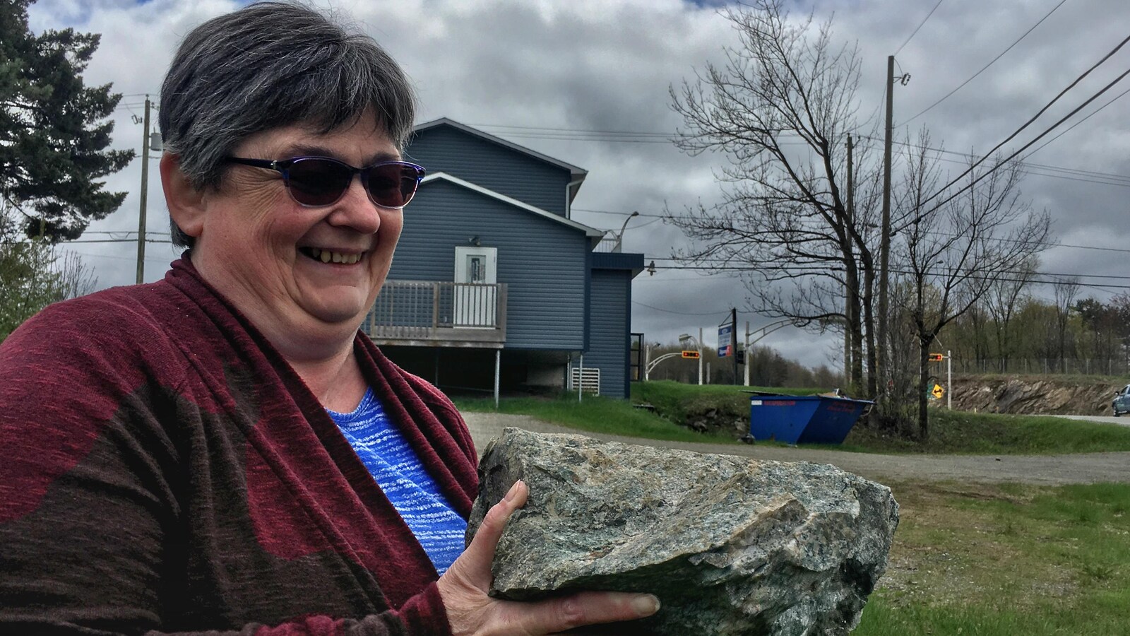 Lucie Huard montre une des roches qui ont été projetées derrière son ancien appartement à plusieurs mètres du site de dynamitage.