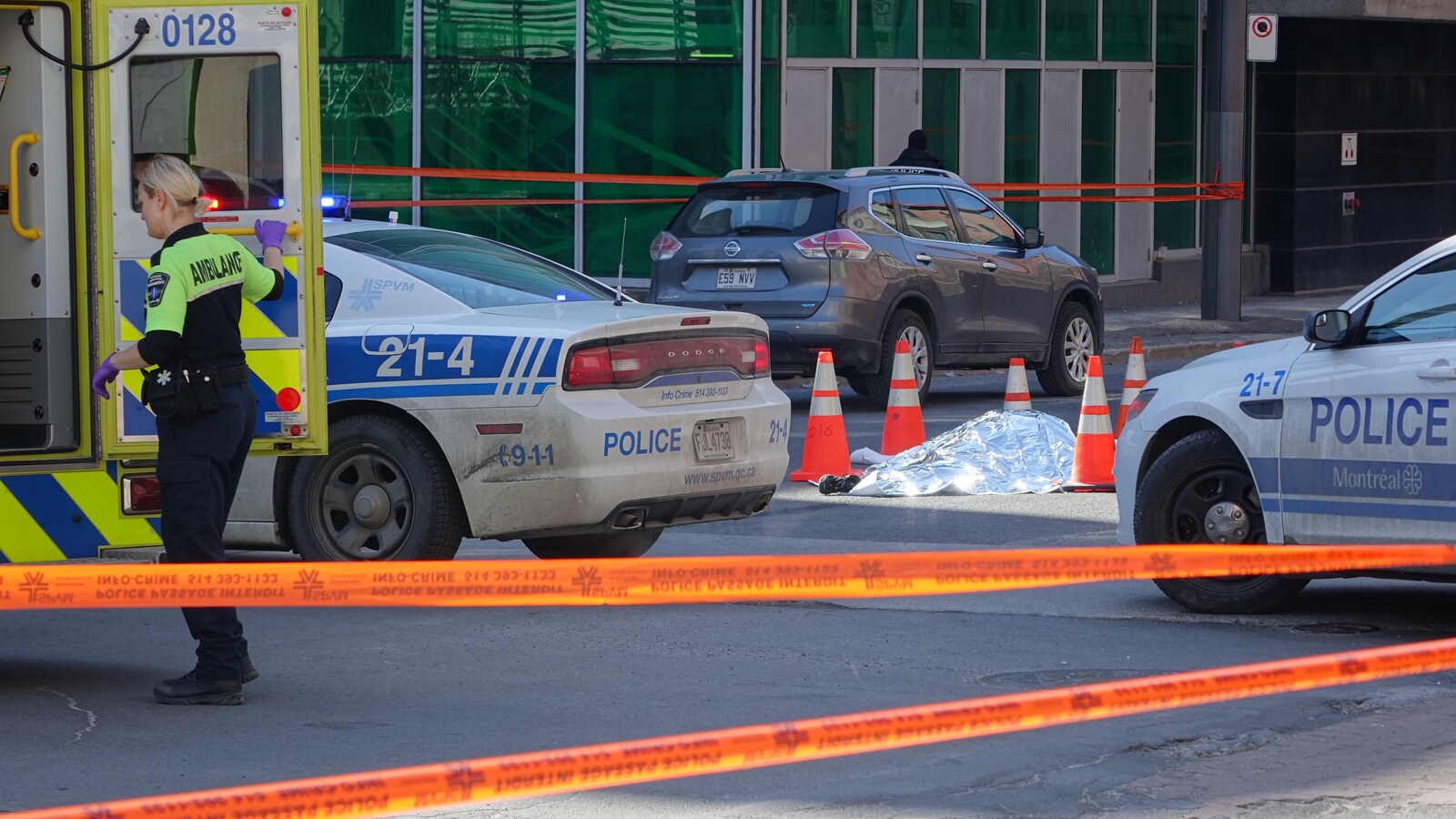 Une couverture argentée recouvre le corps de la victime qui est entouré de voitures de police.