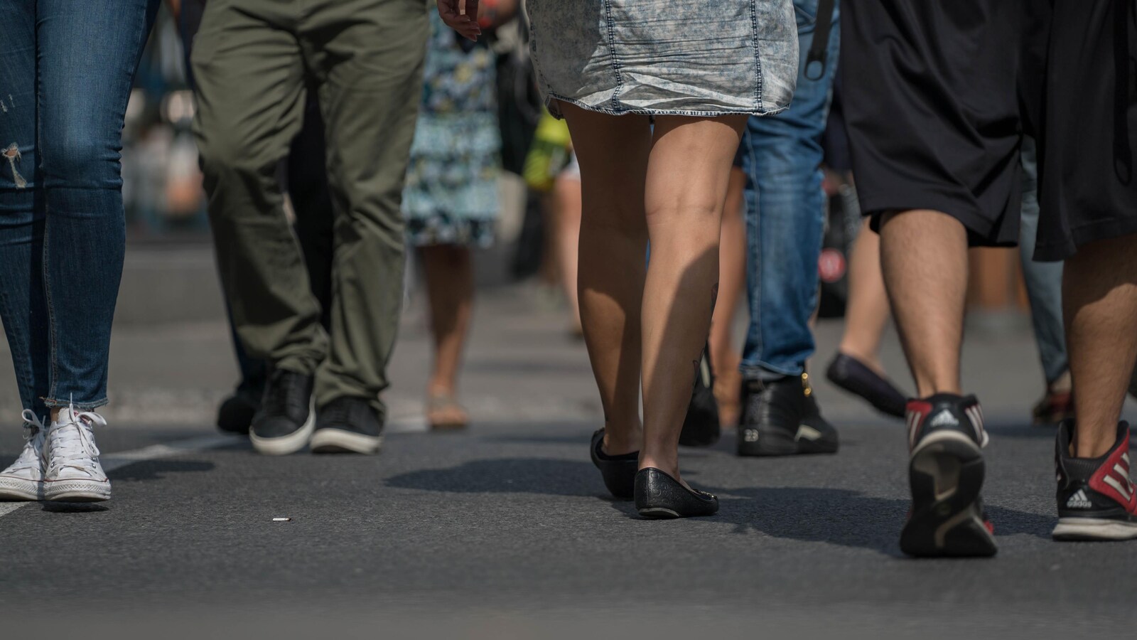 Des piétons marchent dans la rue. On voit uniquement leurs jambes.
