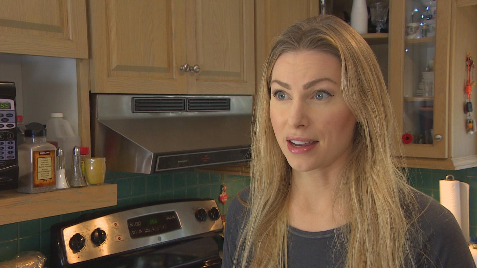 Une femme blonde parle dans une cuisine.