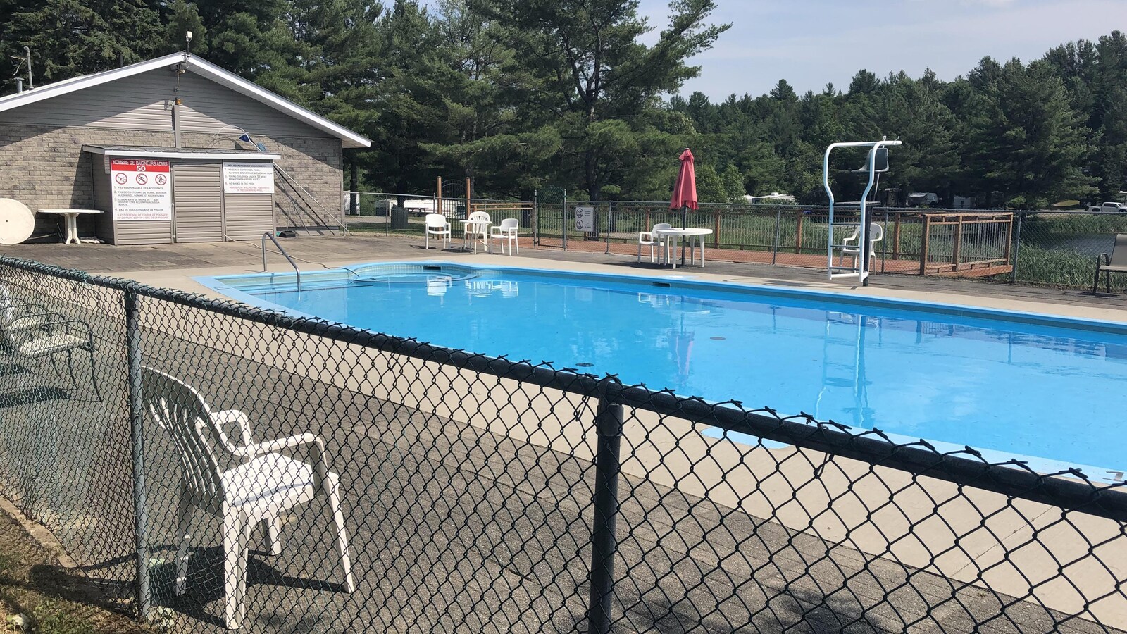Une piscine déserte entourée d'une clôture.