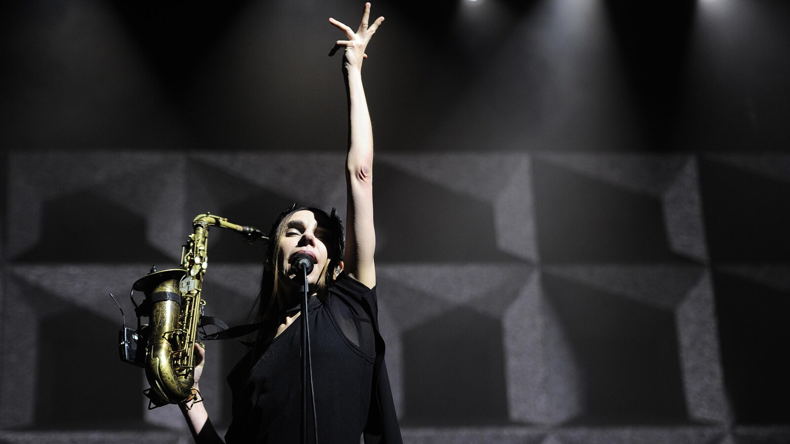 La Britannique PJ Harvey, saxophone dans la main droite, lève le bras gauche pendant qu'elle chante, en concert à Barakaldo, en Espagne, le 28 octobre 2016.