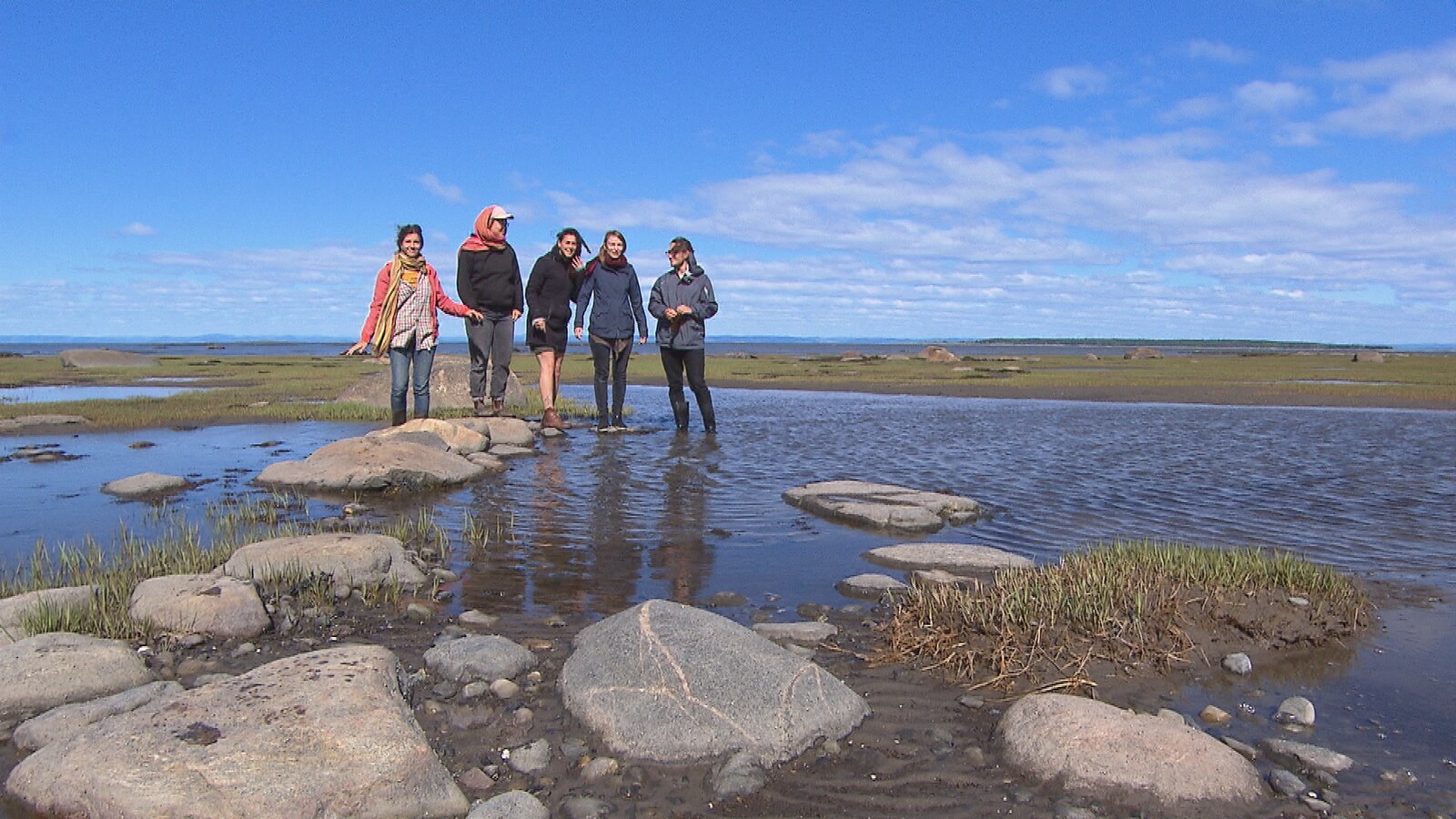 Cinq personnes debout sur une roche près du fleuve