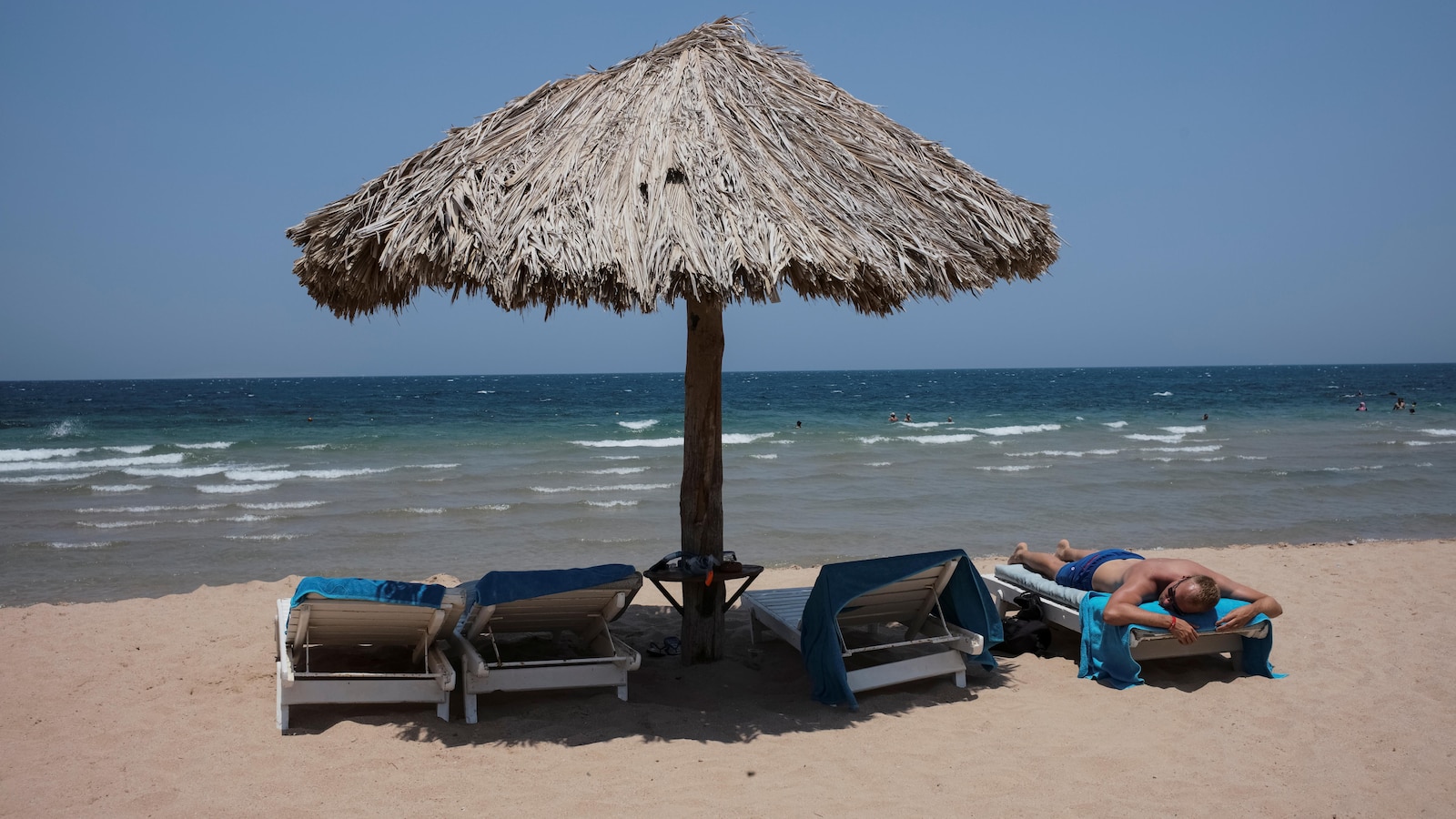 Un homme se fait bronzer sur la plage.