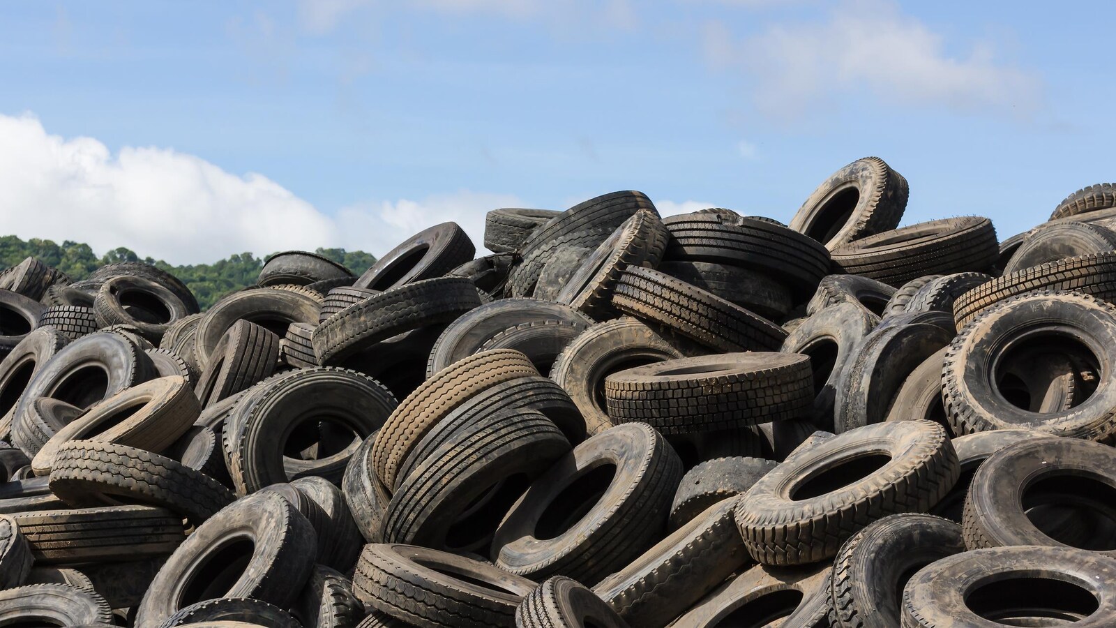 Amas de pneus usagés sur le terrain d'une entreprise de recyclage.