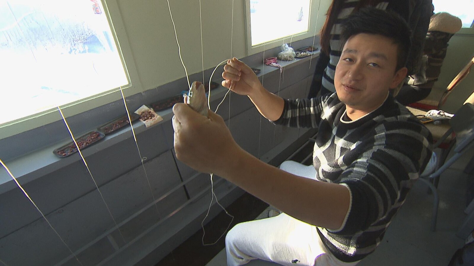 Un citoyen chinois tient dans une main un poulamon qu'il vient de pêcher.
