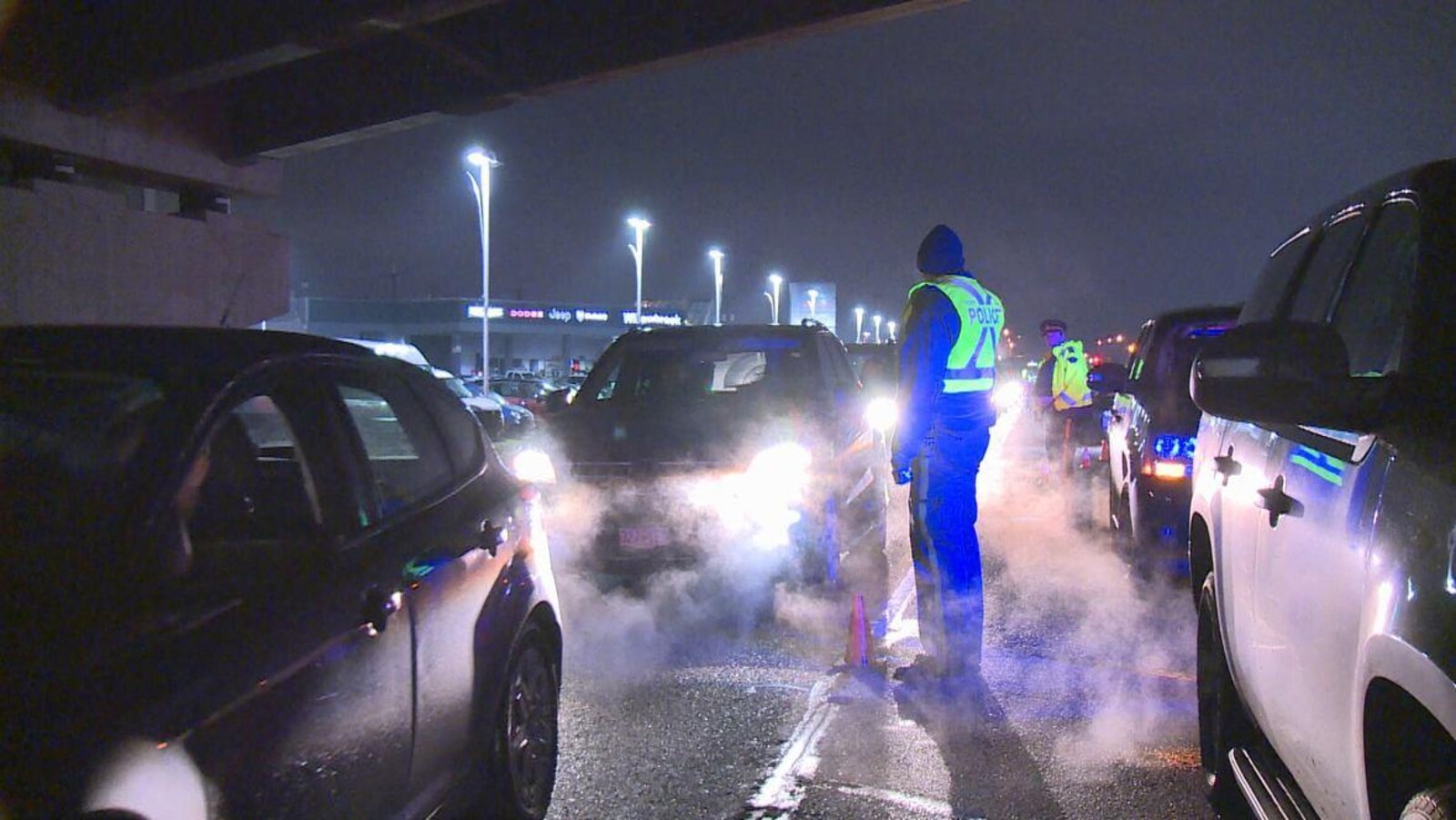 Deux policers, le soir, entre deux files de voiture.