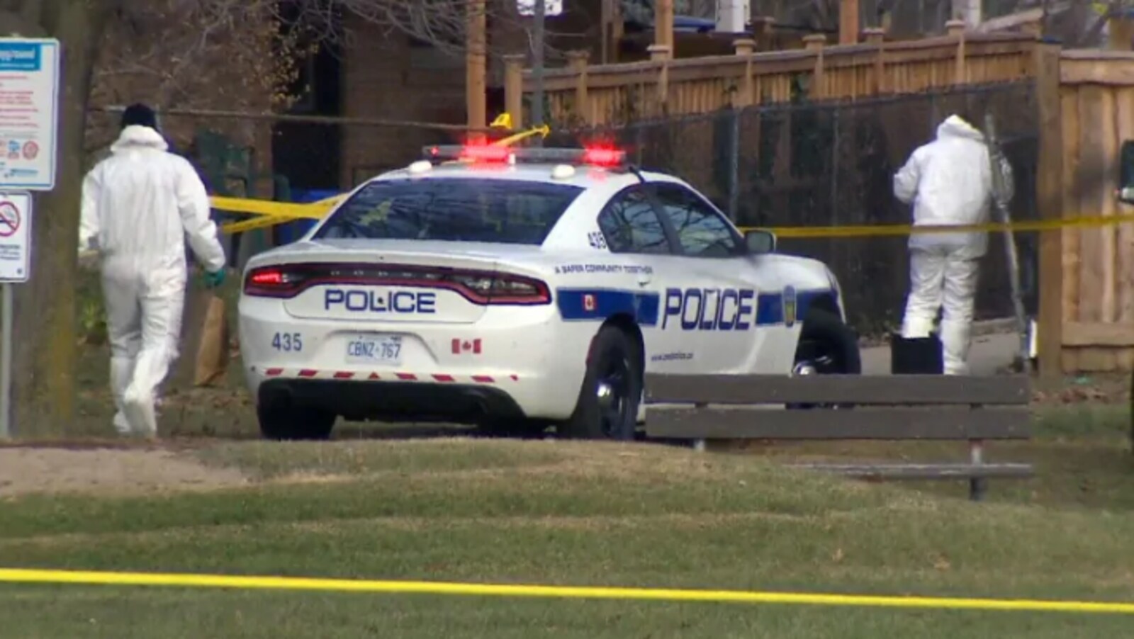 Deux enquêteurs près d'une voiture de police.