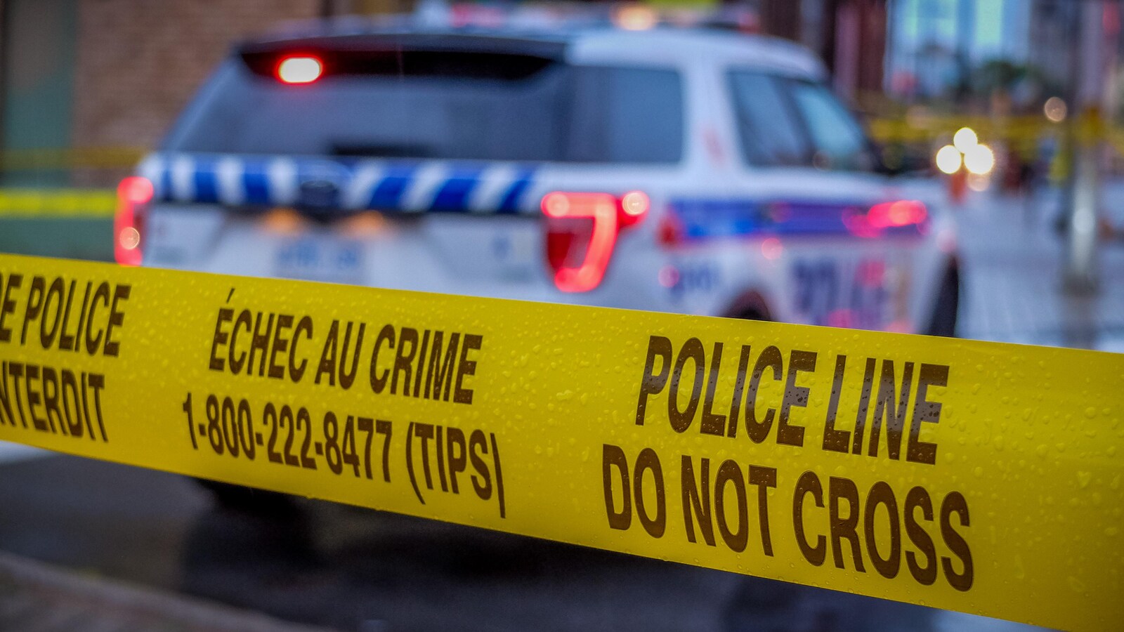 Un ruban jaune devant une autopatrouille de la police.