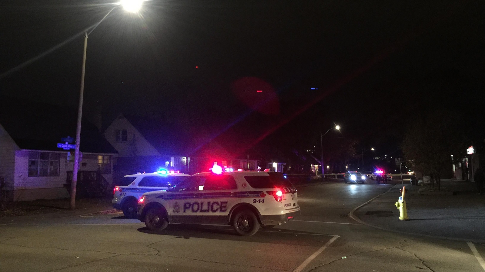 Des véhicules du Service de police d'Ottawa stationnés au coin d'une rue le soir.