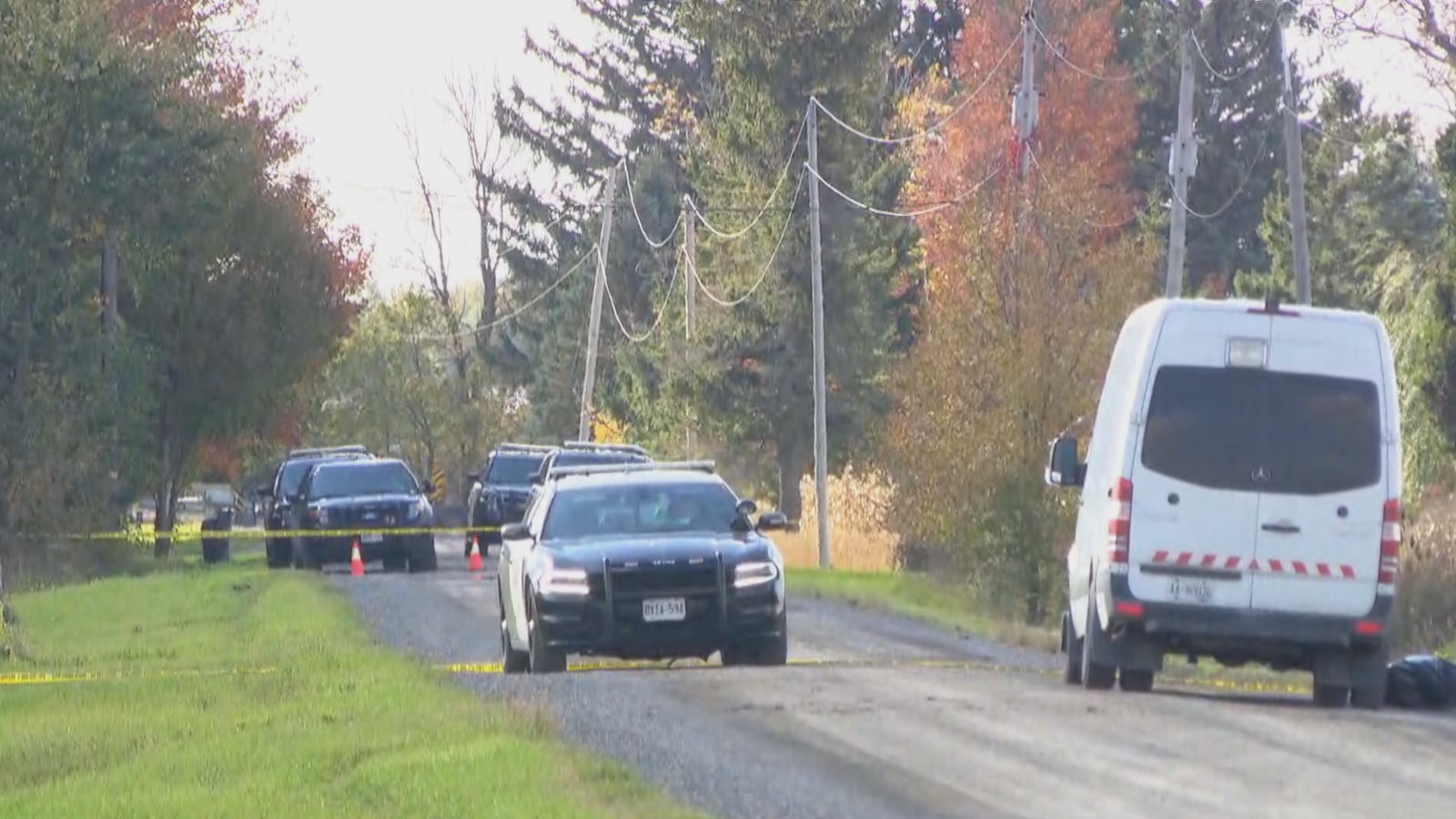 Des voitures de la Police provinciale de l'Ontario sur une chemin de campagne en terre battue.