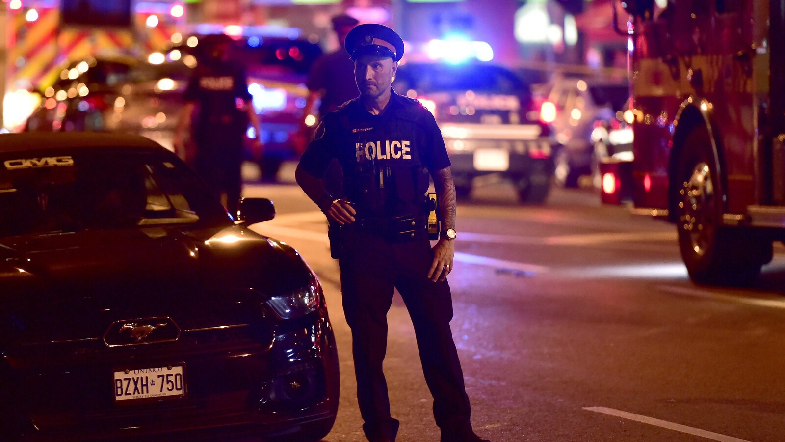 Un policier se tient sur l'avenue Danforth, qui a été le théâtre d'une fusillade, à Toronto.
