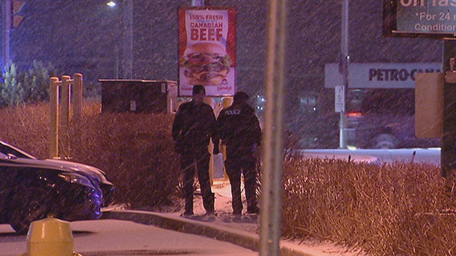 Deux policiers en uniforme debout dans un stationnement commercial