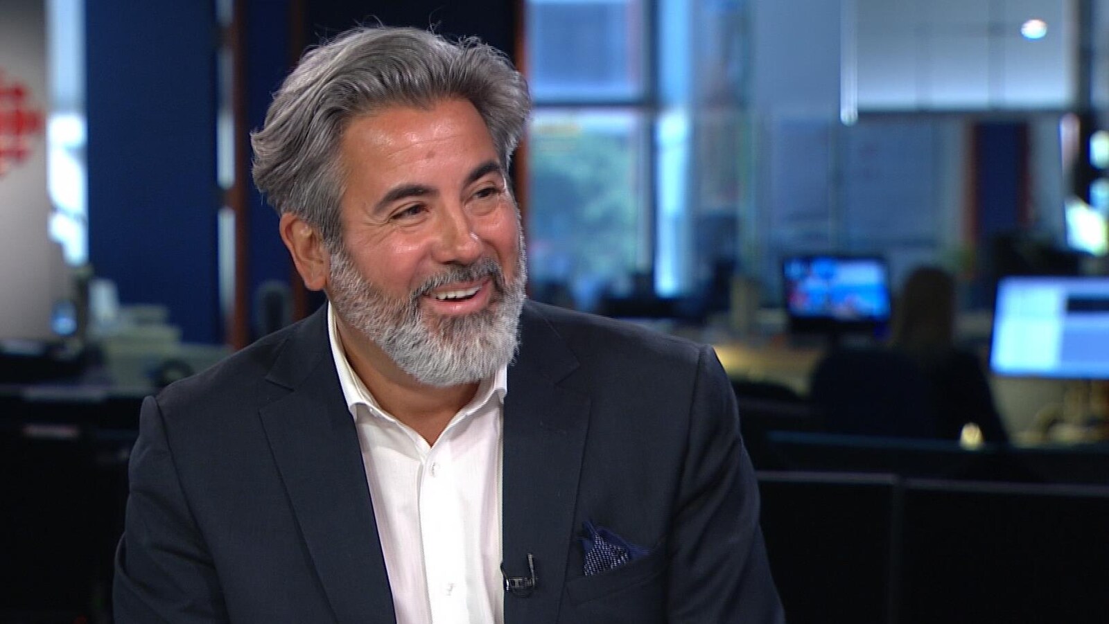 Un homme souriant sur un plateau de télévision.