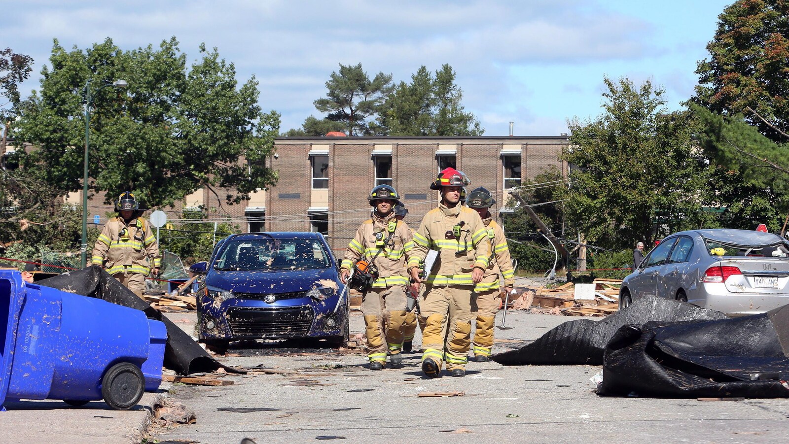 Des pompiers dans une rue avec de nombreux débris.