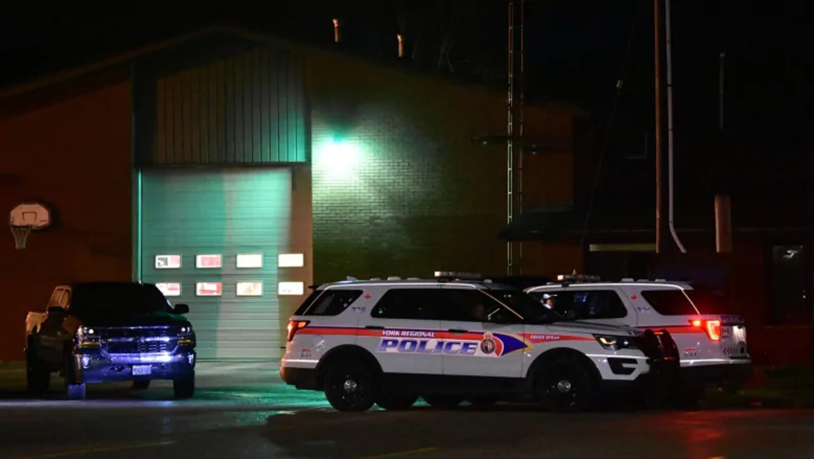 Deux VUS de police blancs devant un édifice en briques brunes